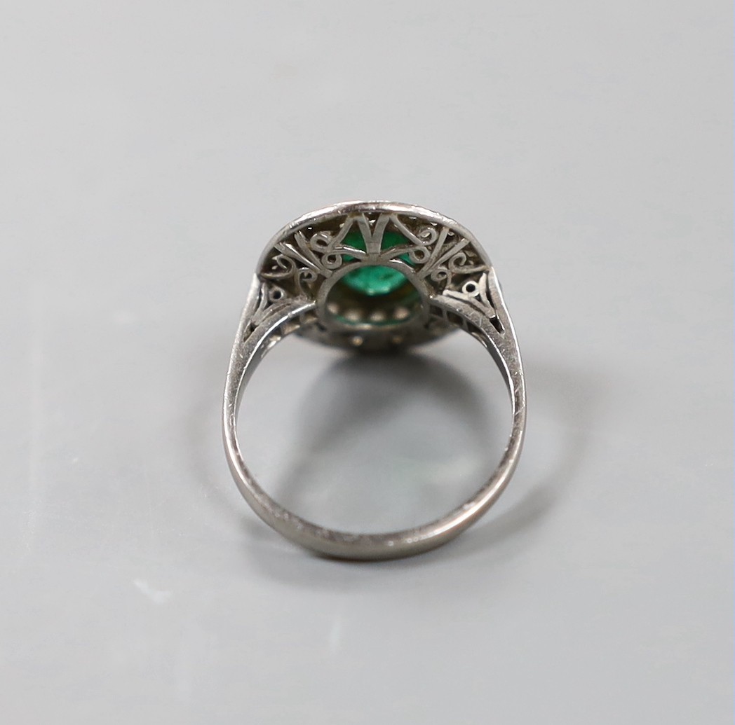 A white metal, emerald and diamond set oval cluster ring, size I/J, gross weight 3.8 grams.